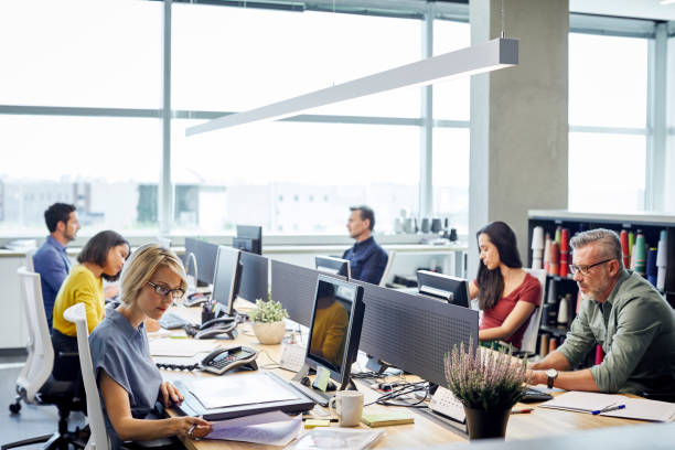 mensen uit het bedrijfsleven werken bij "desk" door windows - kantoor stockfoto's en -beelden