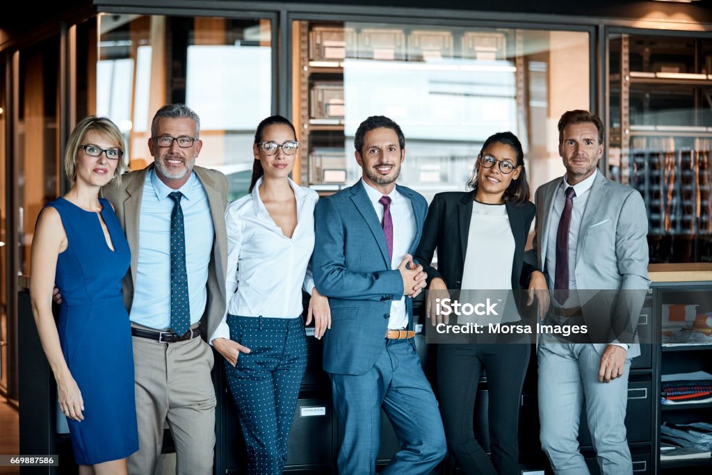 Business people standing in row at textile factory Confident business people standing in row at textile factory. Male and female professionals are smiling in office. They are representing team's unity. Teamwork Stock Photo