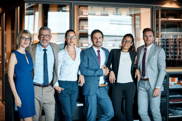 Business people standing in row at textile factory Confident business people standing in row at textile factory. Male and female professionals are smiling in office. They are representing team's unity. 40 44 years photos stock pictures, royalty-free photos & images
