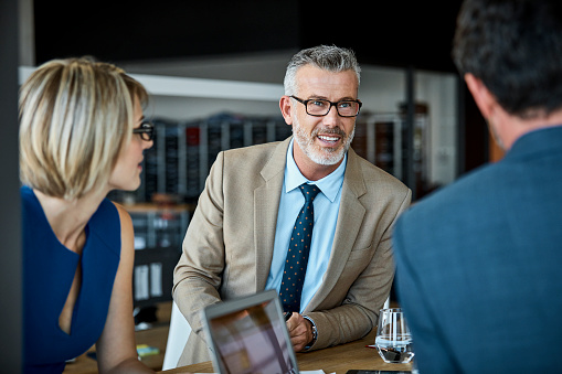 Confident businessman looking at male colleague. Professionals are communicating in textile factory. Male and female executives are working together.