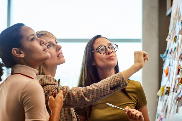 businesswomen looking at fabric samples on board - decyzje zdjęcia i obrazy z banku zdjęć