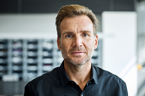 Portrait of confident businessman. Male professional is wearing shirt. He is at textile factory.