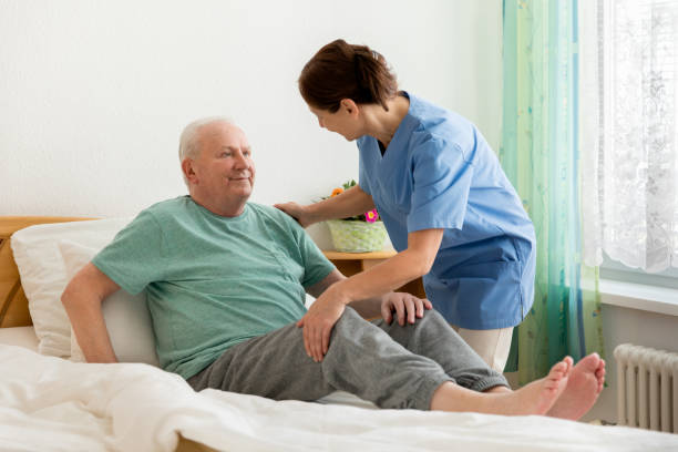 istock Female caregiver helping senior man 669888120