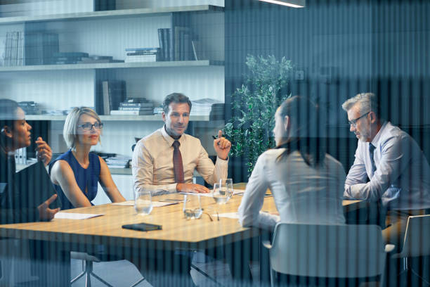 Coworkers communicating at desk seen through glass stock photo