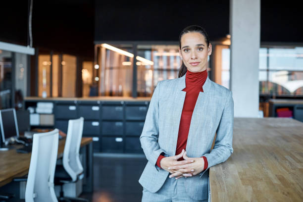Confident female executive in textile factory Portrait of confident female executive leaning on counter. Young businesswoman is standing in textile factory. She is wearing smart casuals. high collar stock pictures, royalty-free photos & images