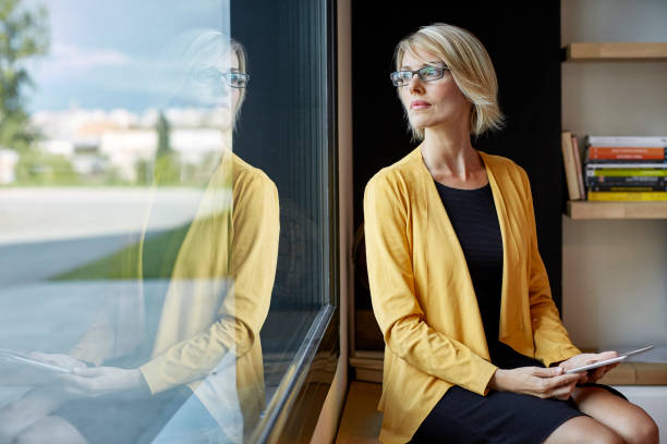 direction avec tablet pc en regardant par la fenêtre - thinking women businesswoman business photos et images de collection