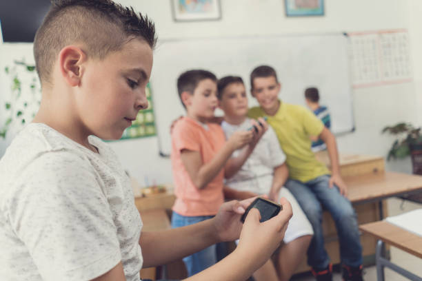 istock Schoolboy playing games on smart phone in the classroom. 669892310