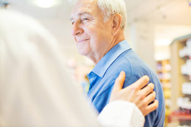 uomo anziano sorridente che guarda il farmacista - mano sulla spalla foto e immagini stock