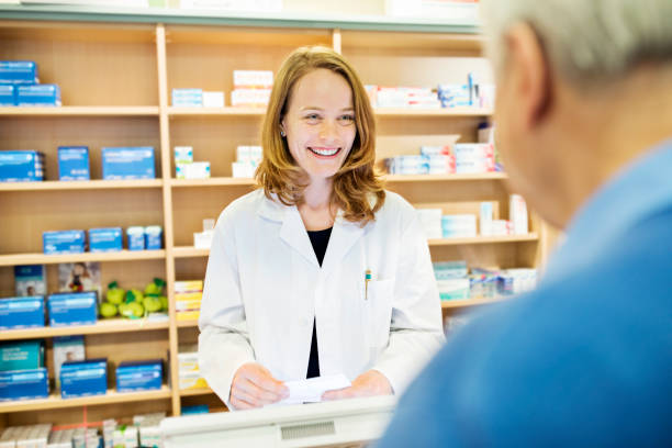 istock Happy pharmacist talking to senior man in store 669898782
