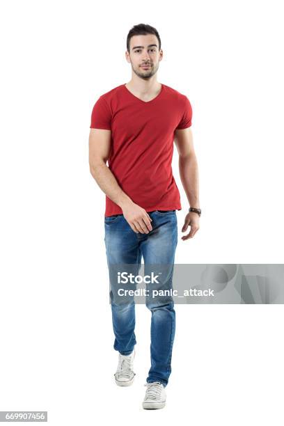 Uomo Casual Rilassato In Jeans E Tshirt Rossa Che Cammina E Guarda La Macchina Fotografica - Fotografie stock e altre immagini di Camminare