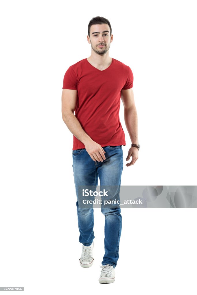 Relaxed casual man in jeans and red t-shirt walking and looking at camera Relaxed casual man in jeans and red t-shirt walking and looking at camera. Full body length portrait isolated over white studio background. Walking Stock Photo