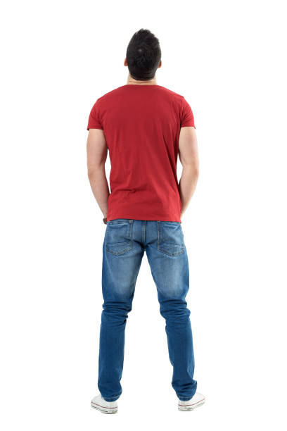 Back view of young casual man with hands in pockets looking up stock photo