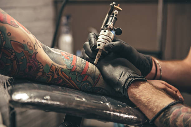 Male doing image on arm close up tattoo machine. Man creating picture on hand with it in salon tattoo photos stock pictures, royalty-free photos & images