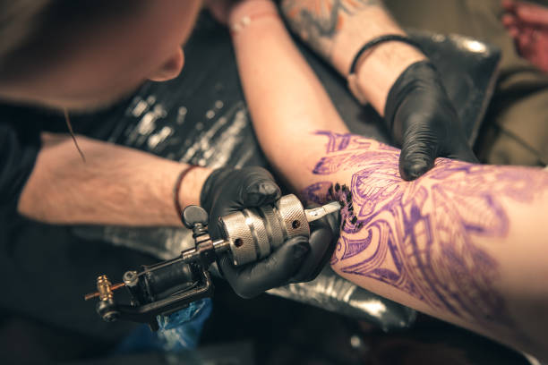 Man creating image on hand Top view of special device which keeping male. He making tattoo on arm of client arm tattoo ideas for men pictures stock pictures, royalty-free photos & images