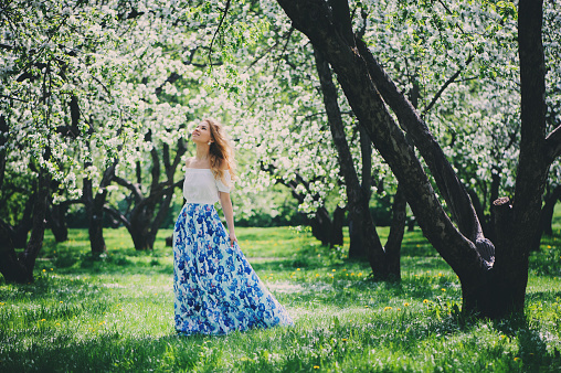 beautiful young woman in floral maxi skirt walking in spring