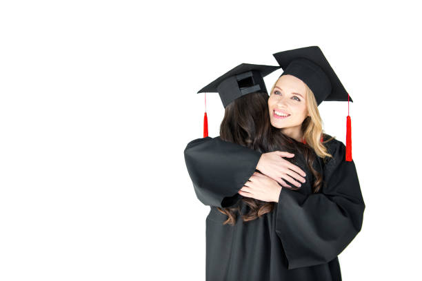 istock Two young happy women in mortarboards hugging on white background 669922670