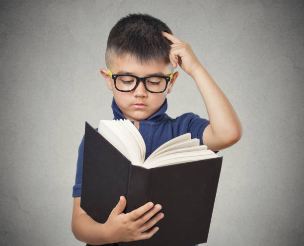 istock closeup portrait child with glasses reading book 669923124