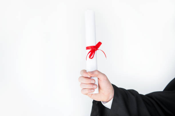 istock Close-up partial view of student holding diploma on white 669923938