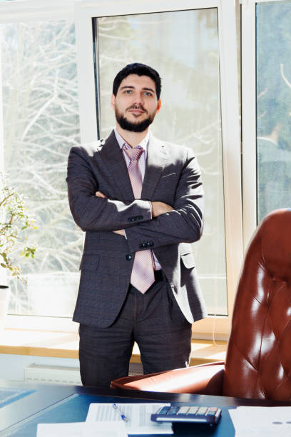 istock A young man standing near a window in the office. 669927658