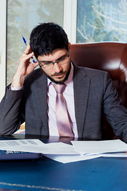 istock A young man sits at a desk in the office and working with papers. 669927704