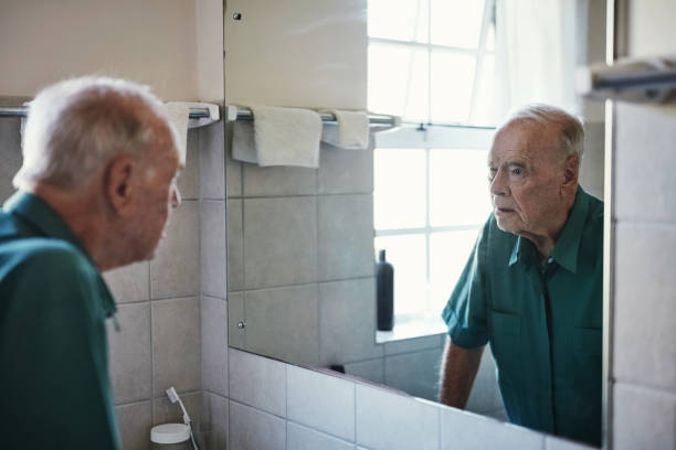 How did I get so old? Shot of a senior man looking in his bathroom mirror vanity mirror photos stock pictures, royalty-free photos & images
