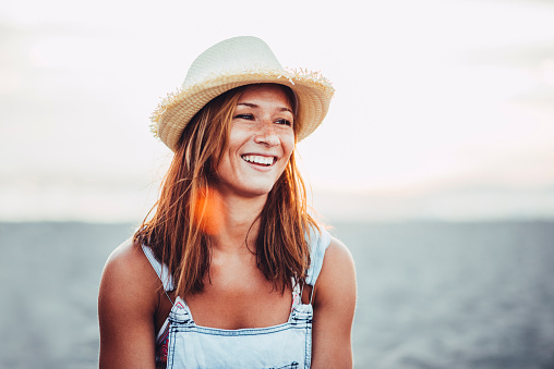 Girl with the hat smiling to the sun.