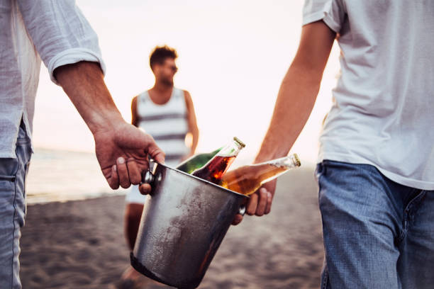 Holding metal beer bucket while walking on sand.