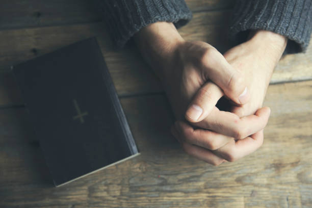 istock Young man  praying and bible on table 669948412
