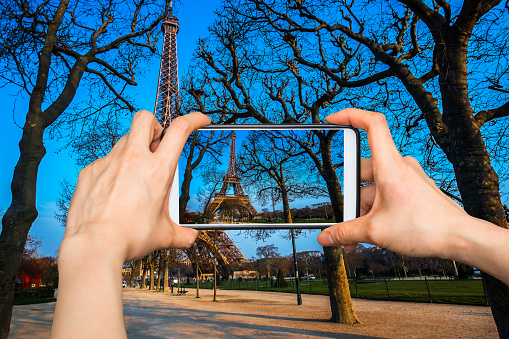 Taking pictures on mobile smart phone in The Eiffel tower is the most visited monument of France.