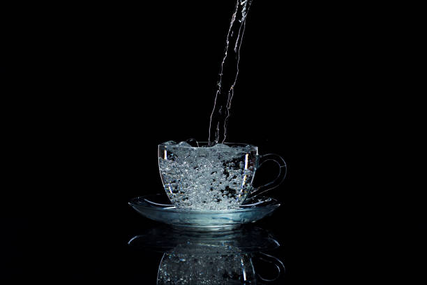 istock Water pours into the cup on a black background, studio light 669959986