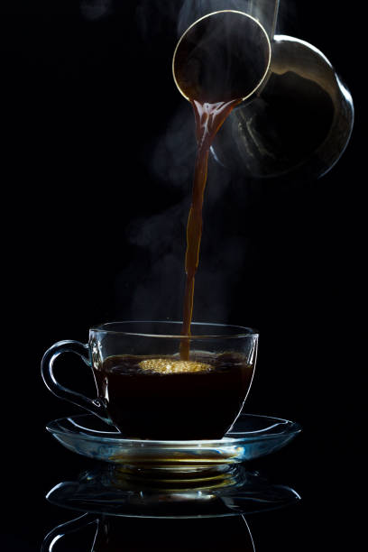 istock Coffee is poured into a glass cup from the Turks, a black background 669962148