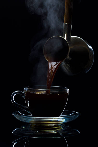 istock Coffee is poured into a glass cup from the Turks, a black background 669962248