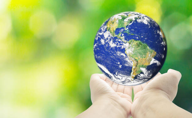 istock holding planet Earth in hands against  green spring background 669963354