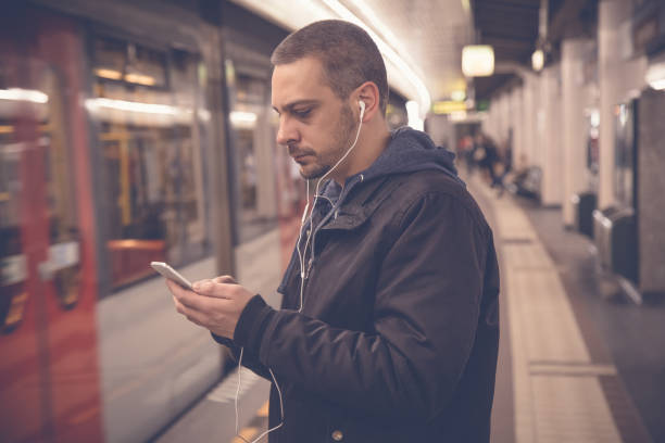 istock Urban man using smartphone and earphones at the train station 669964348