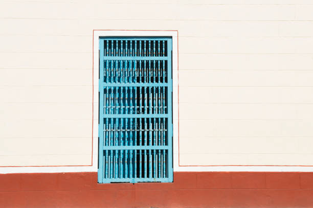 This is a horizontal, color photograph of an exterior wall with a blue window in the historic Iglesia de Nuestra Senora de Regla in Havana, Cuba.