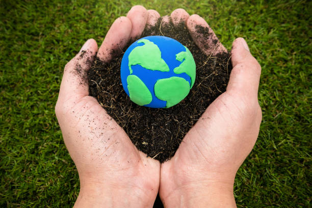 Soil  and earth simulation in hand on grass background, earth day concept