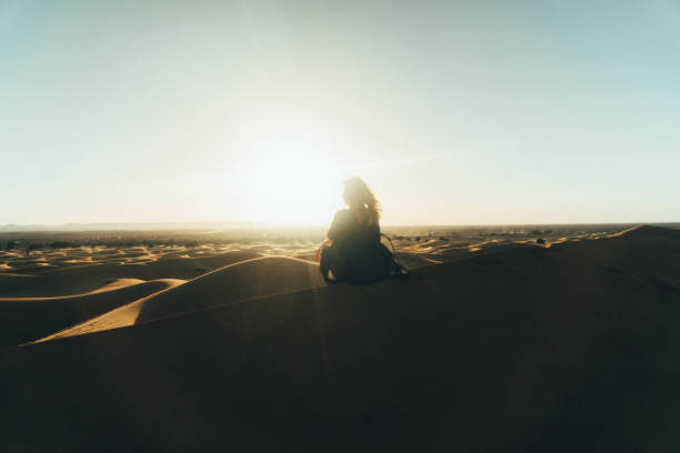 istock Woman sitting on sand  in the desert 669981348