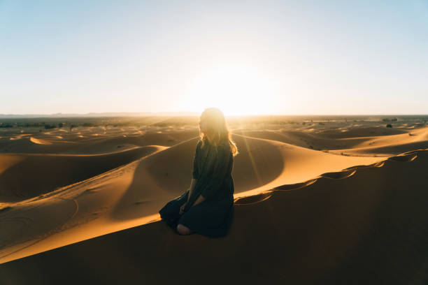 istock Woman sitting on sand  in the desert 669981364