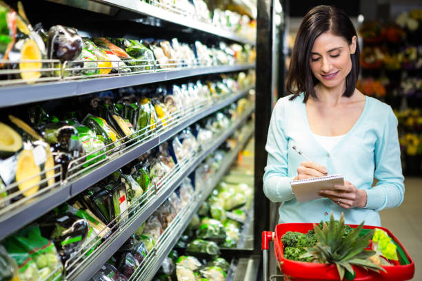 portrait d’une femme souriante faire courses - liste de courses photos et images de collection