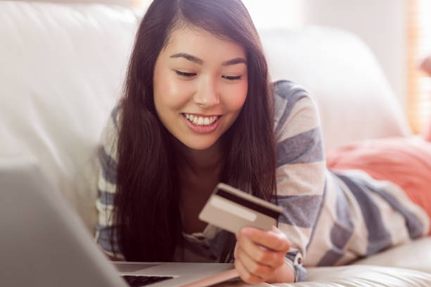 istock Smiling asian woman on couch using tablet to shop online 669985814