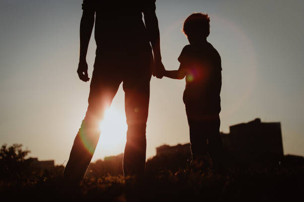 istock silhouette of father and son holding hands at sunset 669996272