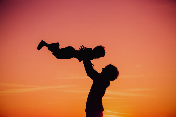 istock father and little son silhouettes play at sunset 670000312
