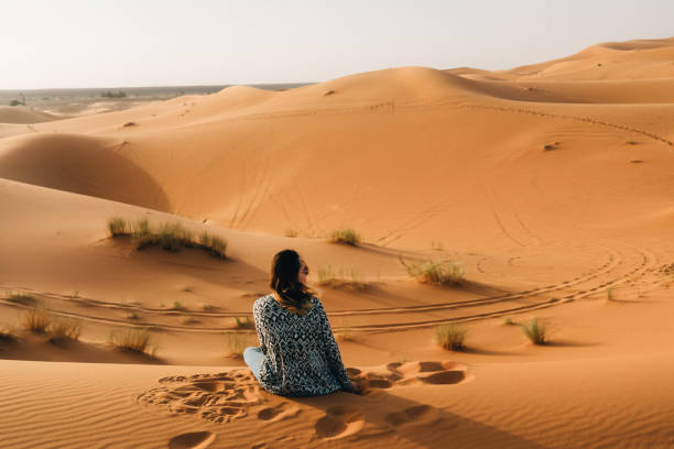 istock Woman sitting on sand in the desert 670001146
