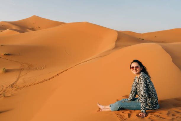 istock Woman sitting on sand in the desert 670001148