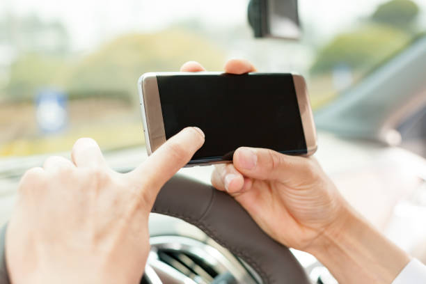 istock man driving car using smart phone/Automobile and smart phone / Driving safe car 670005162