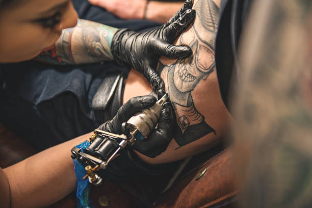 istock Female doing tattoo on belly of man 670015086
