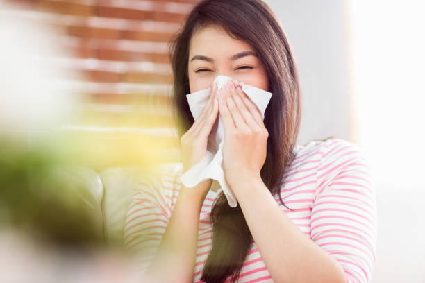 istock Asian woman blowing her nose on couch 670018076
