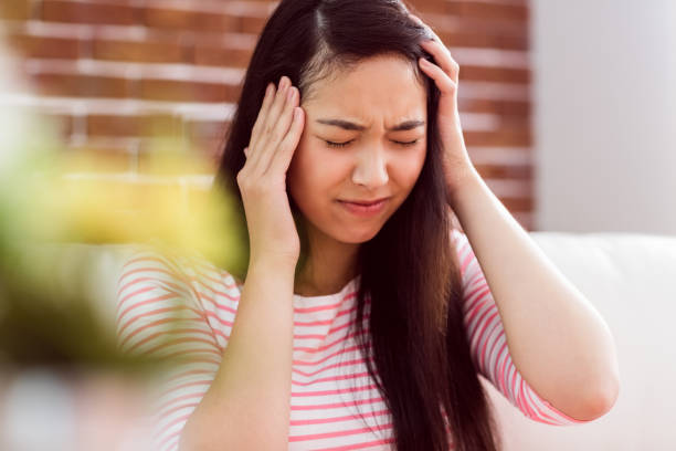 istock Asian woman getting headache on couch 670018302