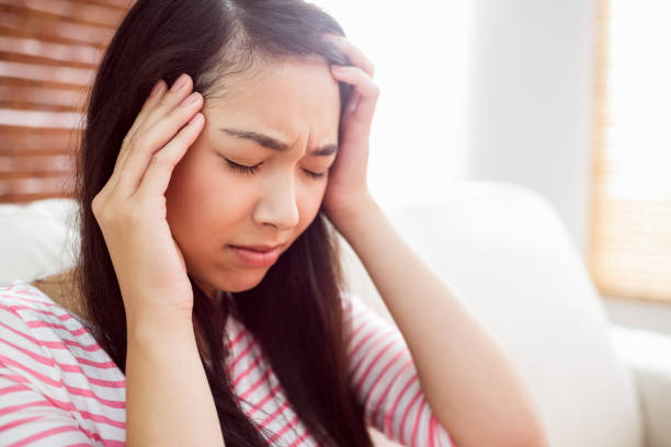 istock Asian woman getting headache on couch 670018540