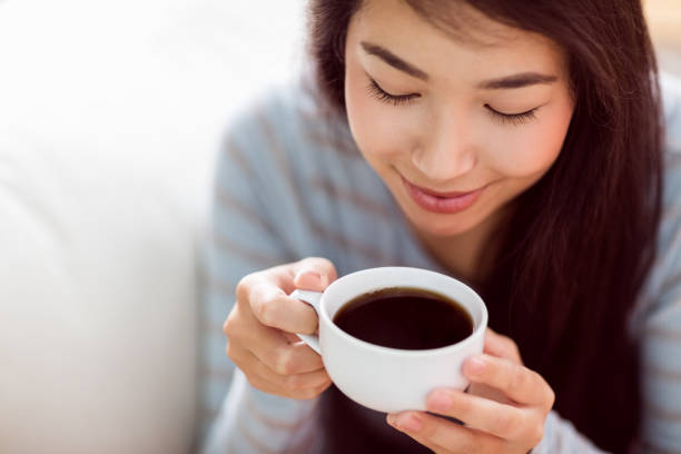 istock Asian woman relaxing on couch with coffee 670019564